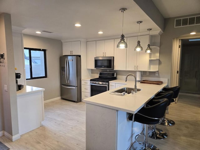 kitchen with sink, stainless steel appliances, white cabinets, decorative light fixtures, and kitchen peninsula