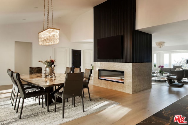 dining room with wood-type flooring, a chandelier, and a high ceiling