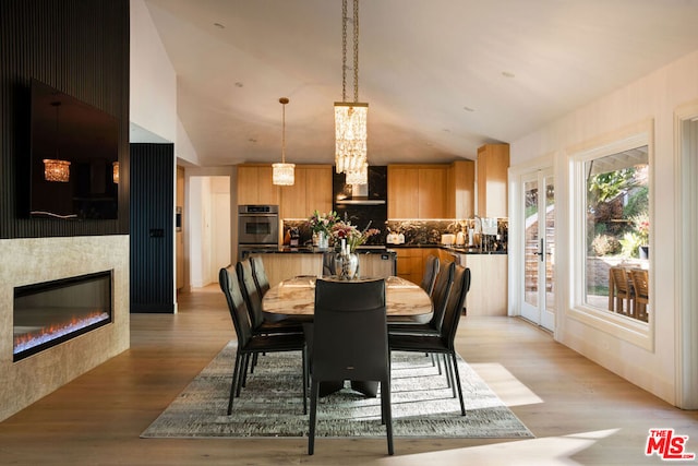 dining space featuring lofted ceiling, sink, and light wood-type flooring