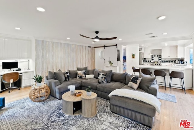 living room featuring ceiling fan, ornamental molding, built in desk, and light hardwood / wood-style flooring