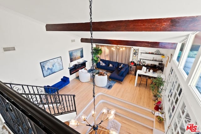 living room featuring hardwood / wood-style flooring, ornamental molding, a chandelier, and vaulted ceiling with beams