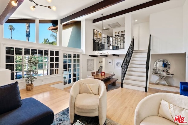 living room with hardwood / wood-style flooring, beamed ceiling, and a high ceiling