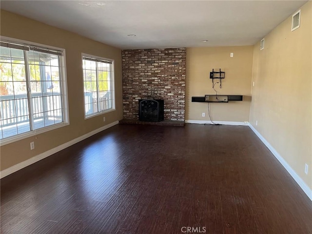 unfurnished living room with a brick fireplace and dark hardwood / wood-style flooring