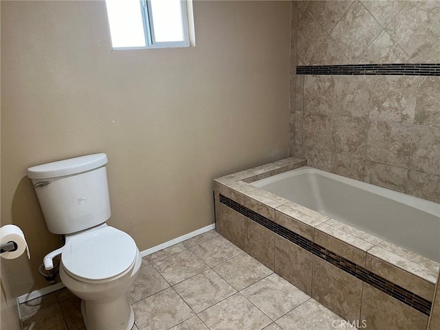 bathroom featuring tile patterned flooring, tiled tub, and toilet