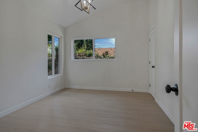 unfurnished room featuring lofted ceiling and light wood-type flooring