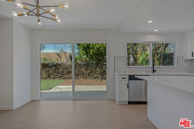 kitchen featuring white cabinetry, tasteful backsplash, hanging light fixtures, light hardwood / wood-style flooring, and dishwasher