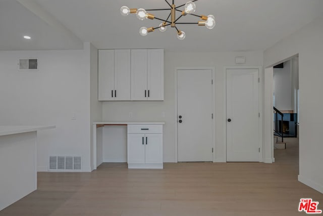 kitchen featuring light hardwood / wood-style floors, hanging light fixtures, and white cabinets