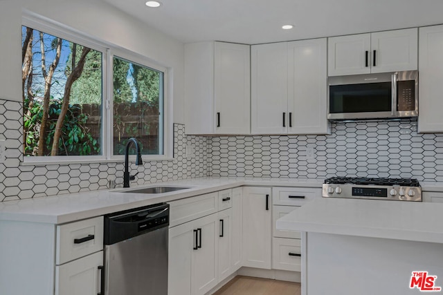 kitchen featuring appliances with stainless steel finishes, sink, white cabinets, and decorative backsplash