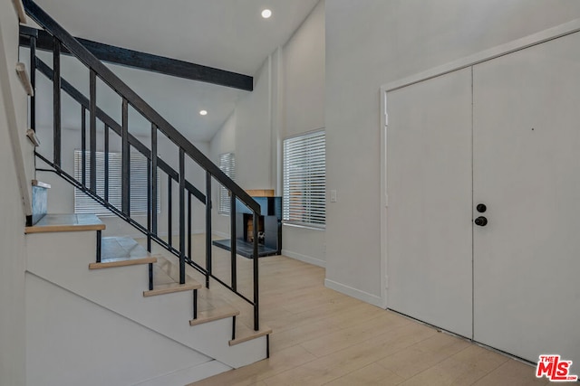 entrance foyer featuring beam ceiling, high vaulted ceiling, and light wood-type flooring