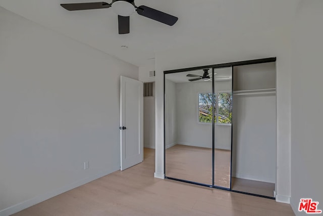 unfurnished bedroom featuring ceiling fan, a closet, and light wood-type flooring