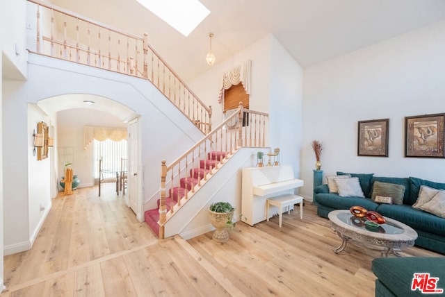 staircase featuring hardwood / wood-style flooring, a high ceiling, and a skylight