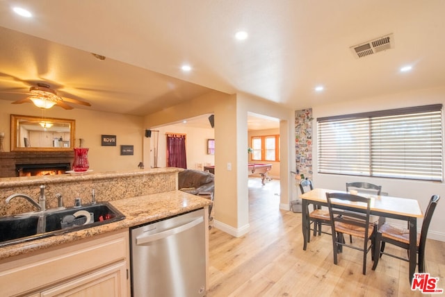 kitchen featuring sink, stainless steel dishwasher, ceiling fan, light stone countertops, and light hardwood / wood-style flooring