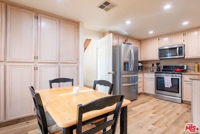 kitchen with light stone counters, stainless steel appliances, and light hardwood / wood-style flooring