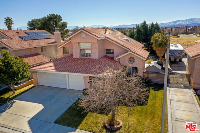 view of front of home featuring a garage, a mountain view, and a front lawn