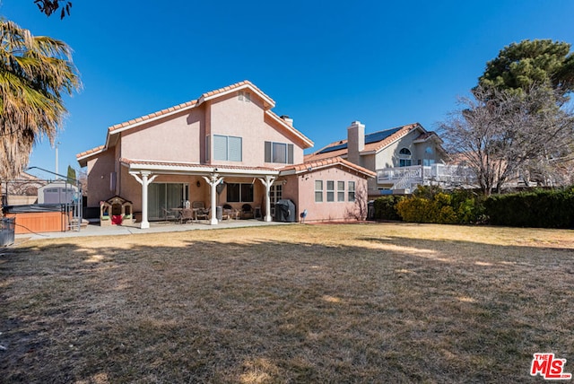 rear view of house with a pergola, a lawn, a hot tub, and a patio