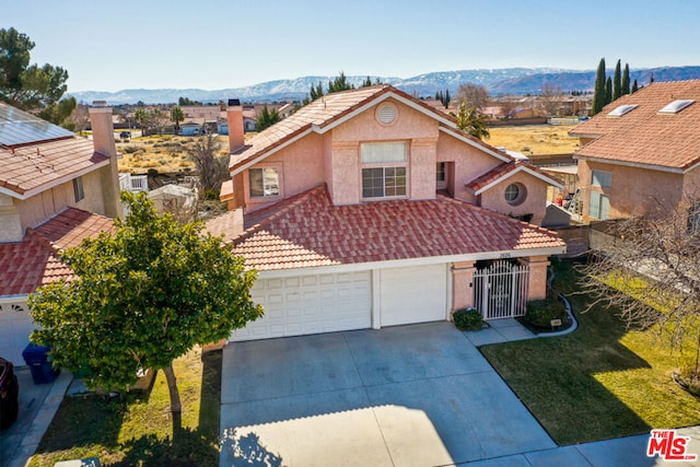 front of property with a garage, a mountain view, and a front yard