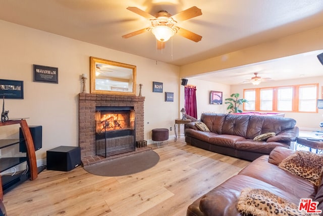 living room with ceiling fan, a brick fireplace, and light hardwood / wood-style floors