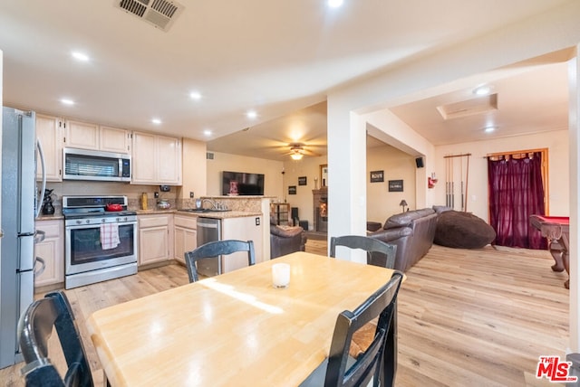 dining area with ceiling fan, sink, and light wood-type flooring