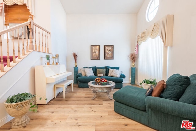 living room with a towering ceiling and light wood-type flooring