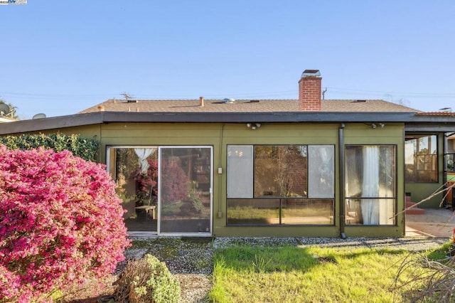 rear view of property with a lawn and a sunroom