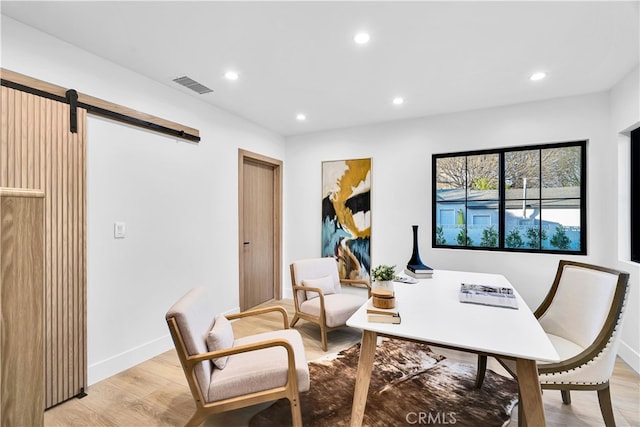 office space featuring a barn door and light hardwood / wood-style flooring