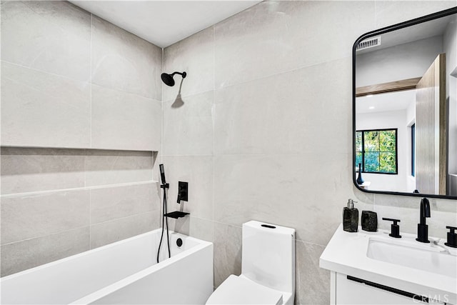 full bathroom featuring vanity, tiled shower / bath, tile walls, and toilet