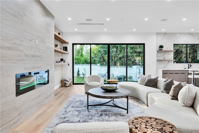 living room with built in shelves, a tile fireplace, and light hardwood / wood-style flooring