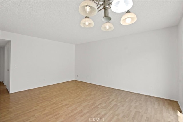 empty room featuring light wood-type flooring and an inviting chandelier