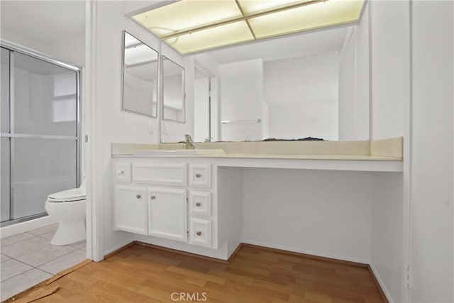 bathroom with vanity, toilet, wood finished floors, and a stall shower