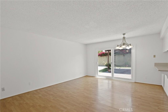 interior space with a textured ceiling, a chandelier, and light wood-style floors
