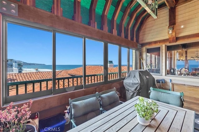 sunroom / solarium featuring vaulted ceiling with beams, plenty of natural light, and a water view