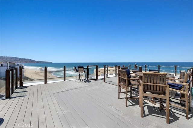 wooden deck featuring a water view and a beach view