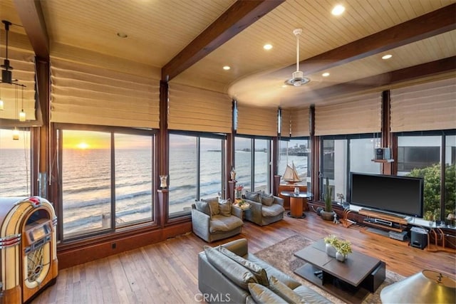 sunroom / solarium featuring a water view, ceiling fan, a wealth of natural light, and beamed ceiling