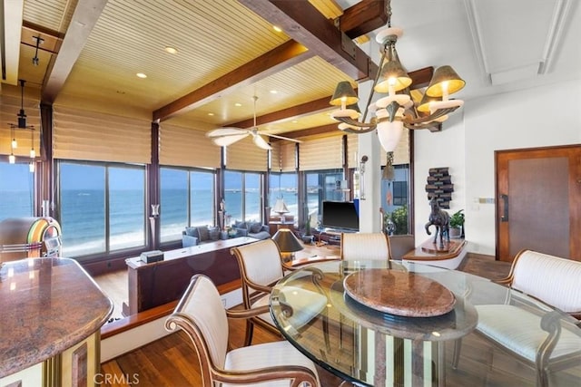 dining space with hardwood / wood-style floors, beam ceiling, a chandelier, and a water view