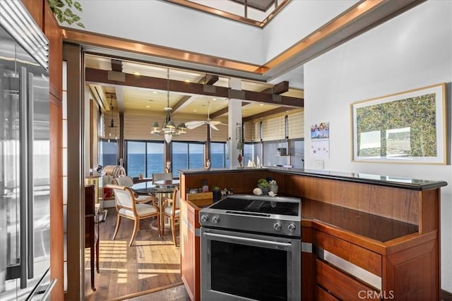 kitchen with pendant lighting, high end appliances, a water view, an inviting chandelier, and light hardwood / wood-style flooring