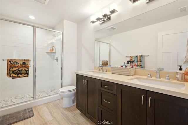 bathroom featuring a shower with door, vanity, hardwood / wood-style flooring, and toilet