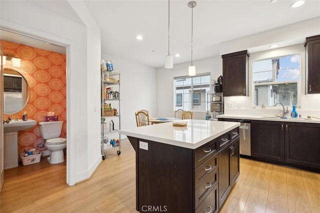 kitchen featuring hanging light fixtures, a kitchen island, dark brown cabinetry, and light wood-type flooring