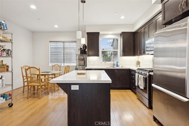 kitchen featuring sink, hanging light fixtures, light hardwood / wood-style flooring, a kitchen island, and stainless steel appliances