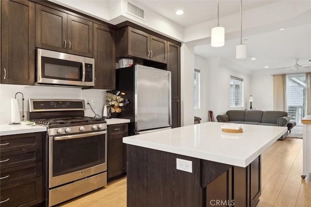 kitchen featuring light hardwood / wood-style flooring, stainless steel appliances, a center island, dark brown cabinetry, and decorative light fixtures