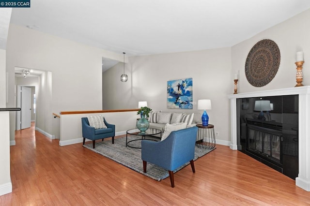 living room featuring lofted ceiling, wood-type flooring, and a fireplace