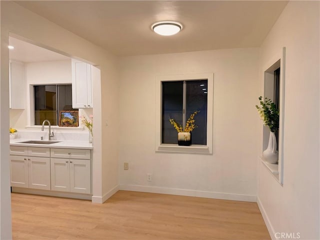 kitchen featuring white cabinetry, sink, and light hardwood / wood-style flooring