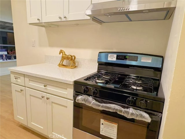 kitchen with ventilation hood, light hardwood / wood-style flooring, white cabinets, and black gas range