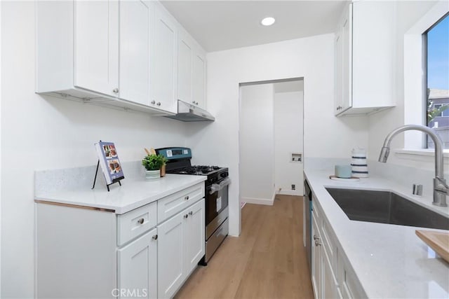 kitchen with a sink, white cabinets, light wood finished floors, and gas stove
