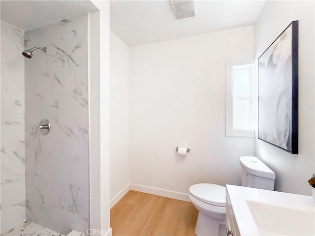 bathroom featuring vanity, baseboards, a marble finish shower, toilet, and wood finished floors