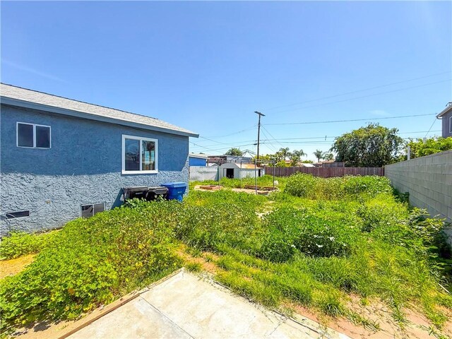 view of yard featuring an outdoor structure, fence, and a storage unit