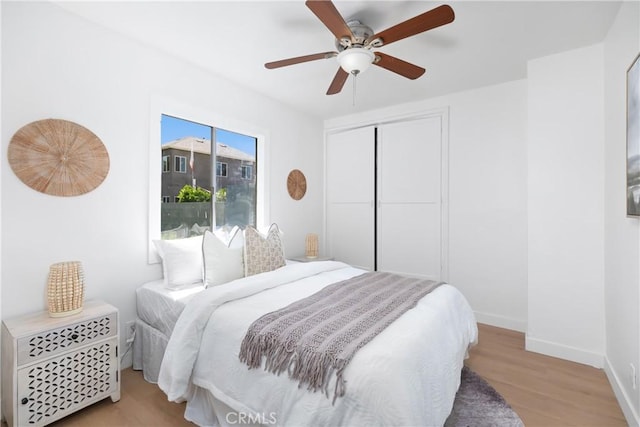 bedroom with a closet, ceiling fan, wood finished floors, and baseboards