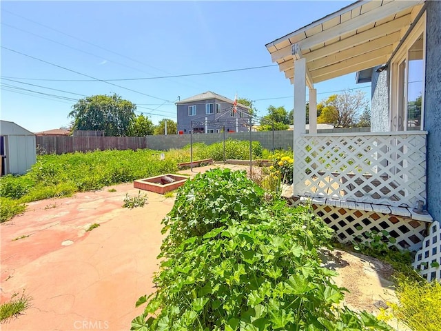 view of yard with a garden, a shed, an outdoor structure, fence, and a patio