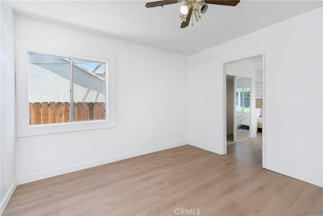 unfurnished room with light wood finished floors, ceiling fan, and baseboards