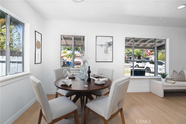 dining space with light wood-style flooring, a healthy amount of sunlight, and baseboards