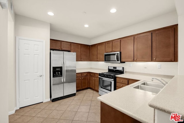 kitchen featuring sink, light tile patterned floors, kitchen peninsula, and appliances with stainless steel finishes